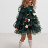 Pige iført mørkegrøn julekjole i tyl med guldkanter og juledetaljer til børn