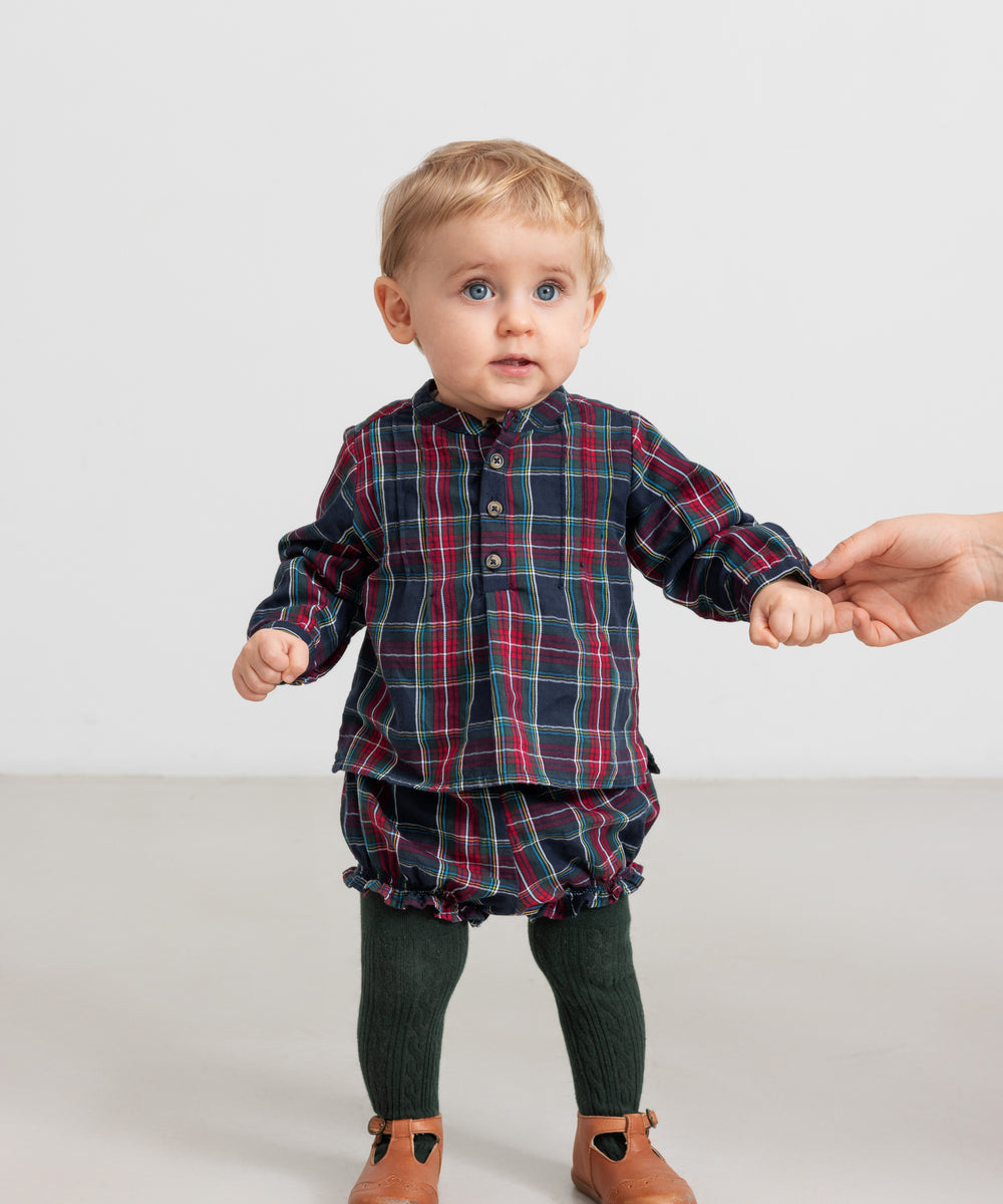 Baby iført mørkeblå og rød ternet skjorte og bloomers