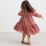 Pige iført rosa festkjole i tyl med guldprint og flæser til børn