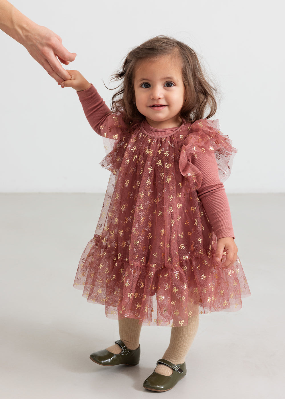 Baby iført støvet rosa body og festlig lyserød mønstret tylkjole