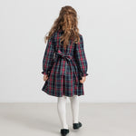 Pige iført ternet julekjole og cremefarvede strømpebukser til børn