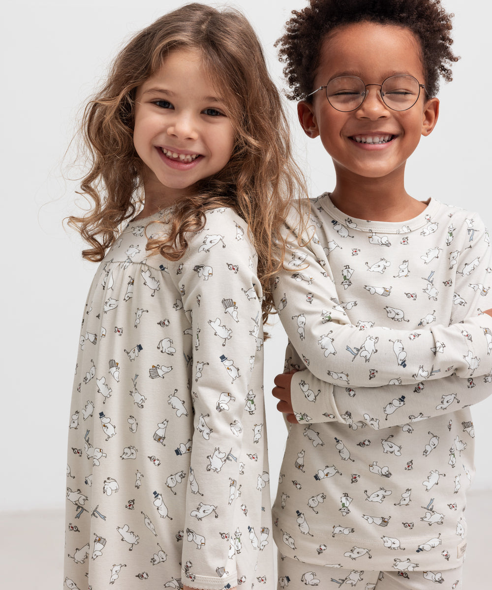 To glade børn iført nattøj med Moomin-print, stående sammen
