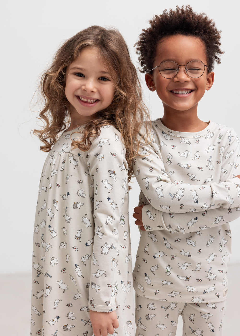 To glade børn iført nattøj med Moomin-print, stående sammen