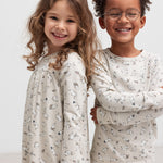 To glade børn iført nattøj med Moomin-print, stående sammen