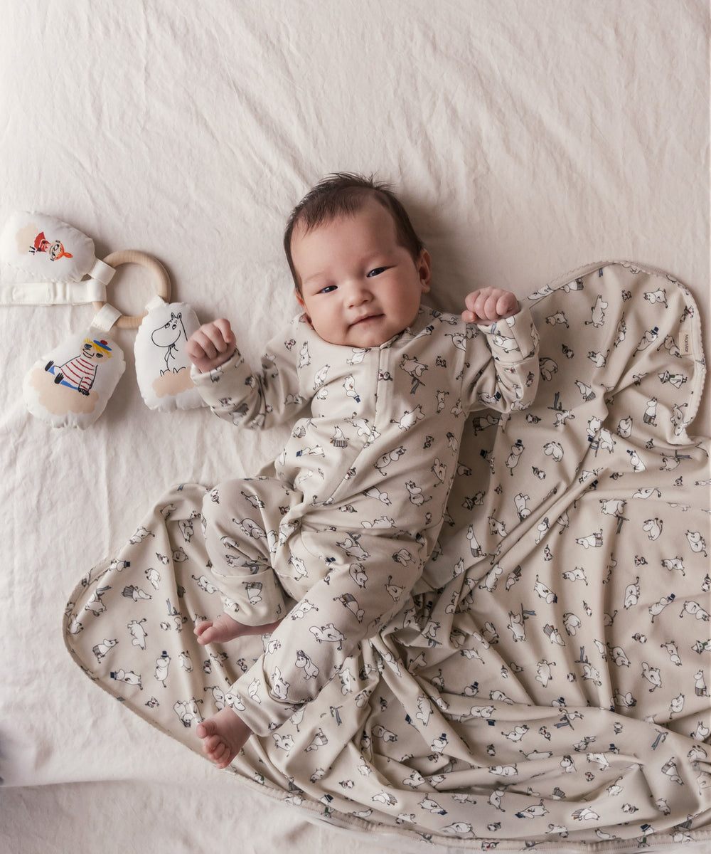 Baby ligger på baby tæppe med Moomin-print