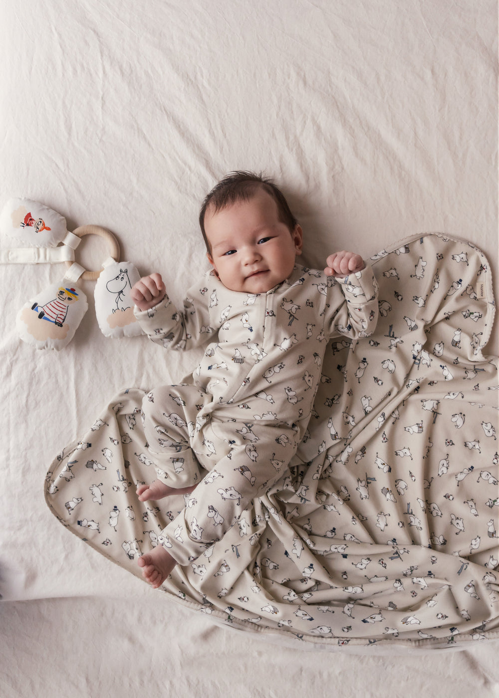 Baby ligger på baby tæppe med Moomin-print