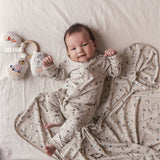 Baby iført heldragt med lange ærmer, trykknapper og Moomin-tryk i lyse farver