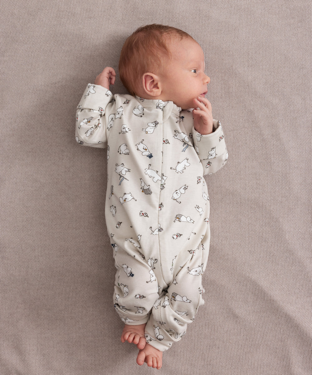 Baby iført lys heldragt med Moomin-mønster