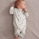 Baby iført lys heldragt med Moomin-mønster