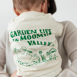 Baby wearing a white t-shirt with a green Moomin print.