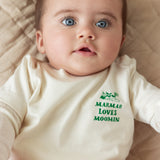 Baby wearing a white t-shirt with a green Moomin print.