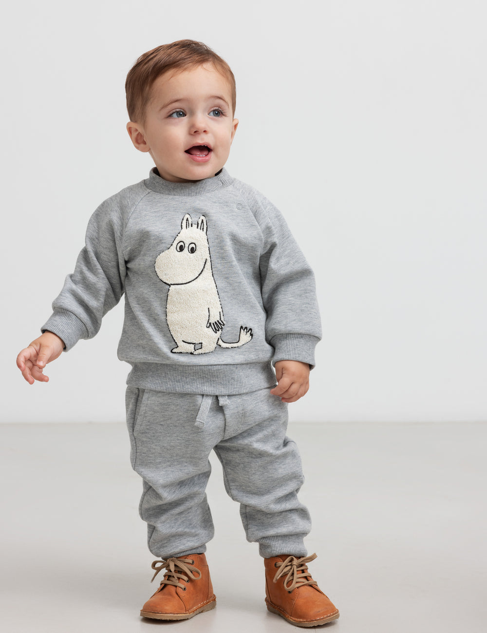 Baby iført grå trøje med Moomin print foran