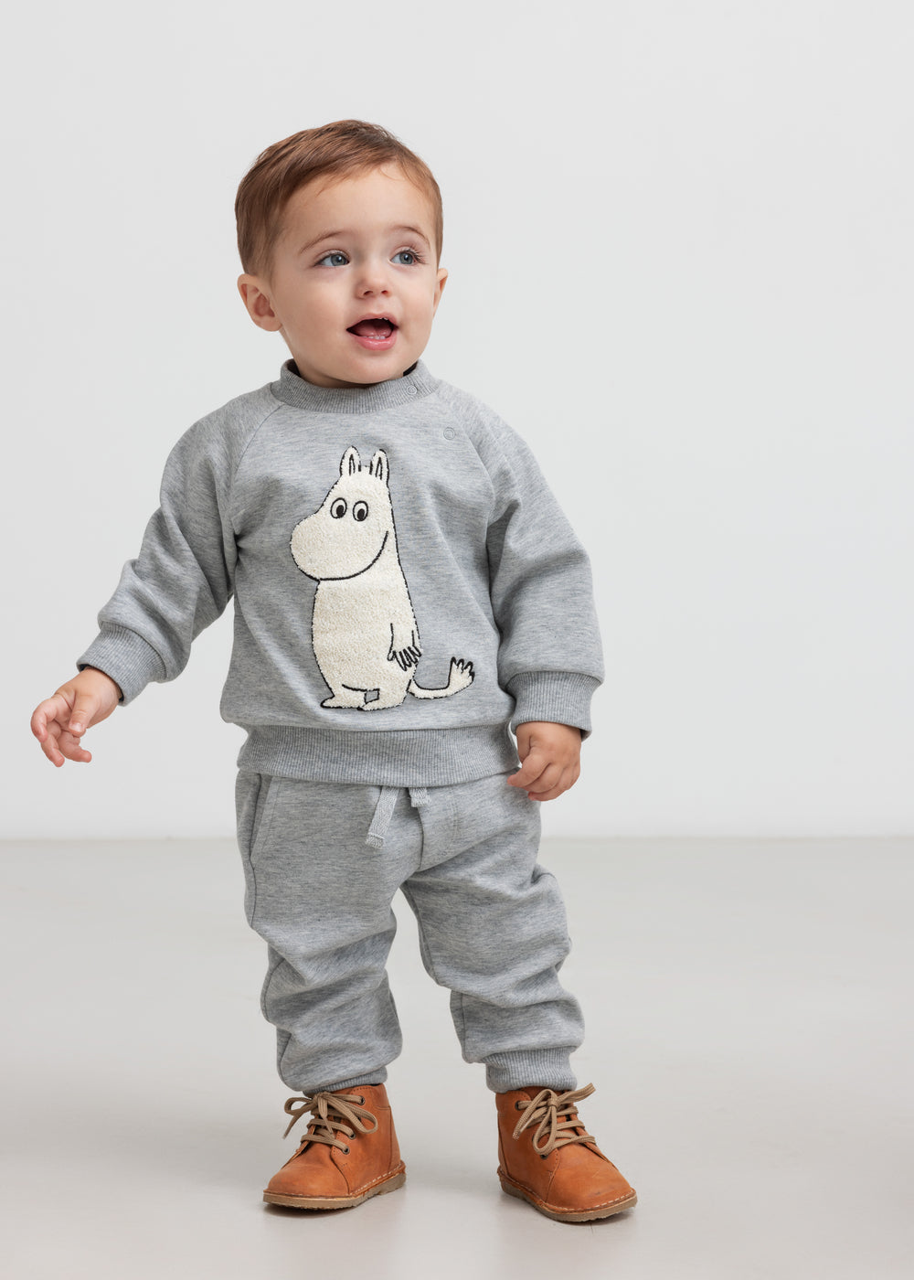 Baby iført grå trøje med Moomin print foran