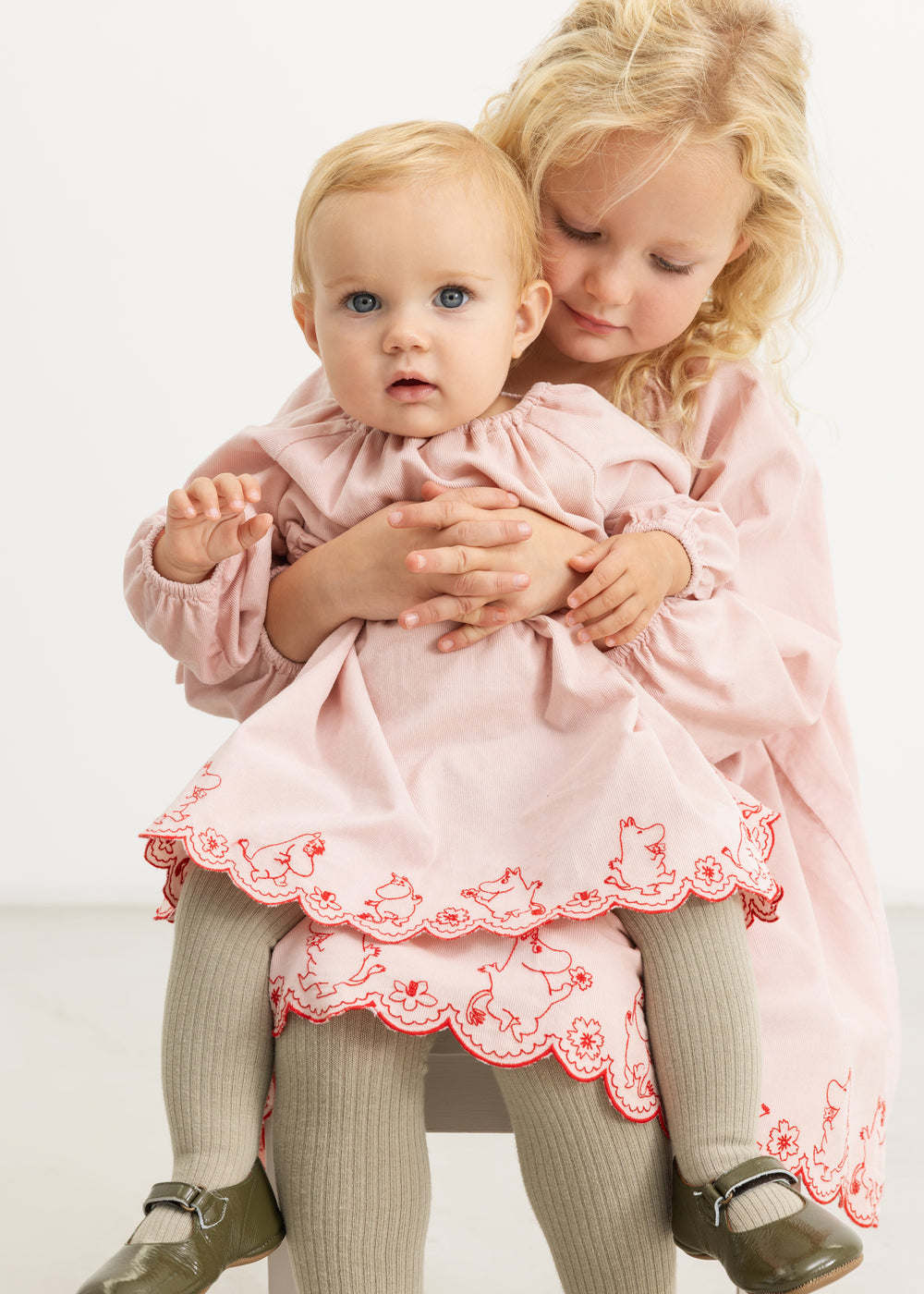 Pink dress with red patterned hem and print on the skirt, front view, full figure.