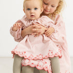 Pink dress with red patterned hem and print on the skirt, front view, full figure.