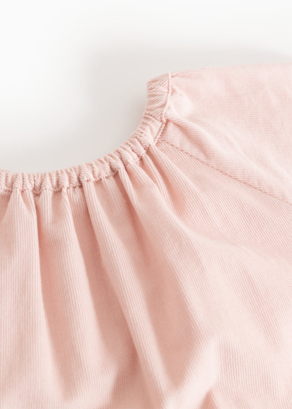 Pink dress with a ruffled neckline and delicate ruffled details at the shoulder.