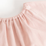 Pink dress with a ruffled neckline and delicate ruffled details at the shoulder.