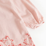 Pink dress with red embroidered pattern edge and wavy bottom edge.