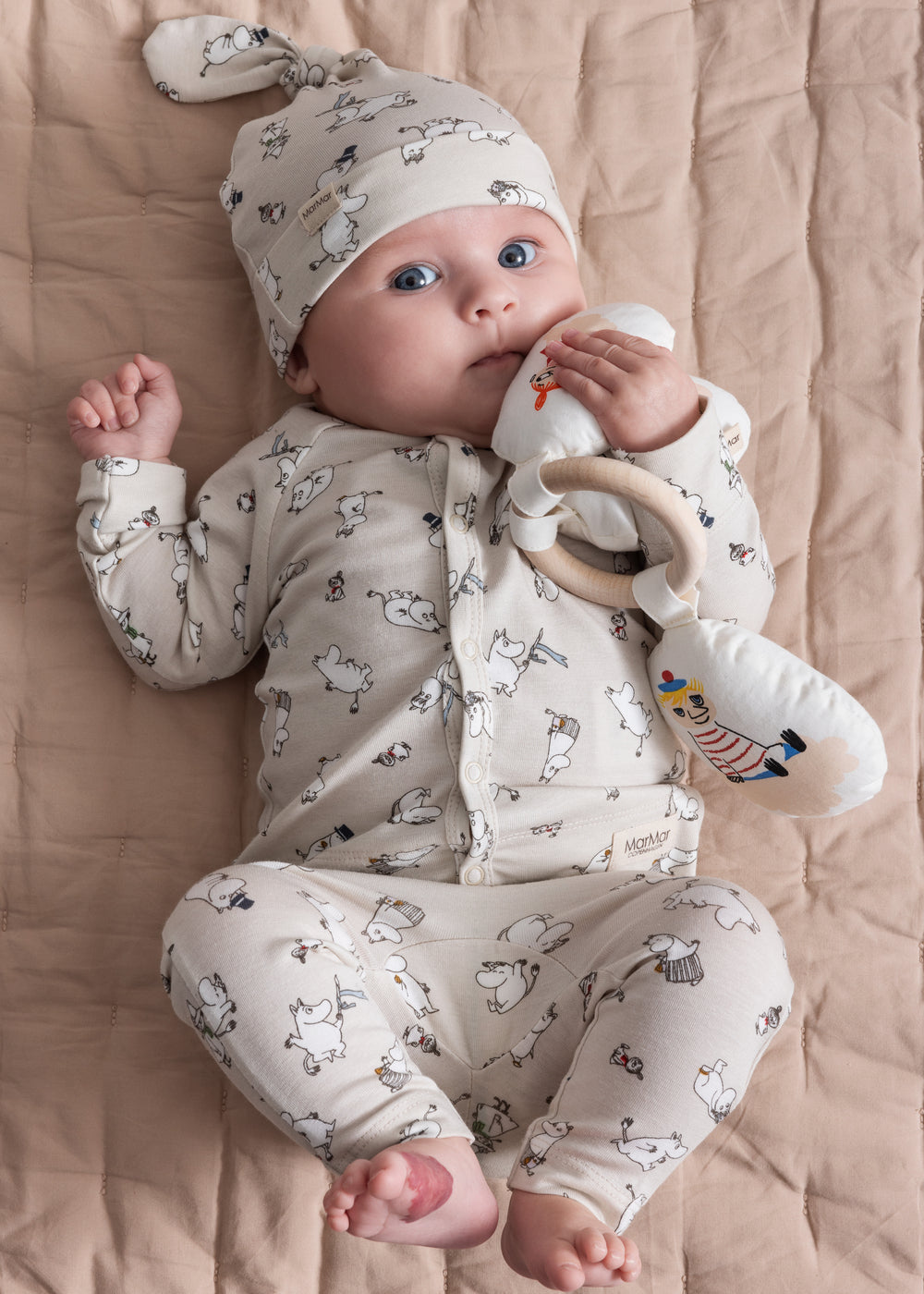 Baby iført lyst Moomin-print bukser og hue