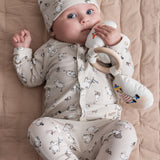 Baby iført langærmet Moomin-body med hat liggende på lyst underlag