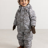 Child in a gray winter suit with dark brown knitted gloves and brown boots