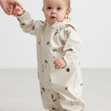 Baby wearing a beige raincoat with Moomin print and hood.