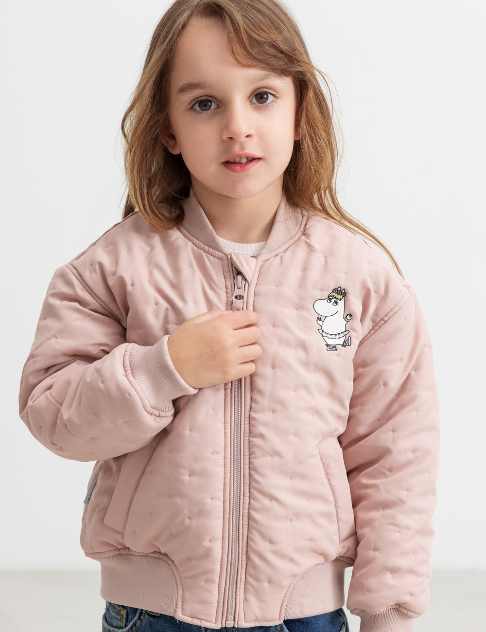 Child wearing a bright red quilted jacket with Moomin print.