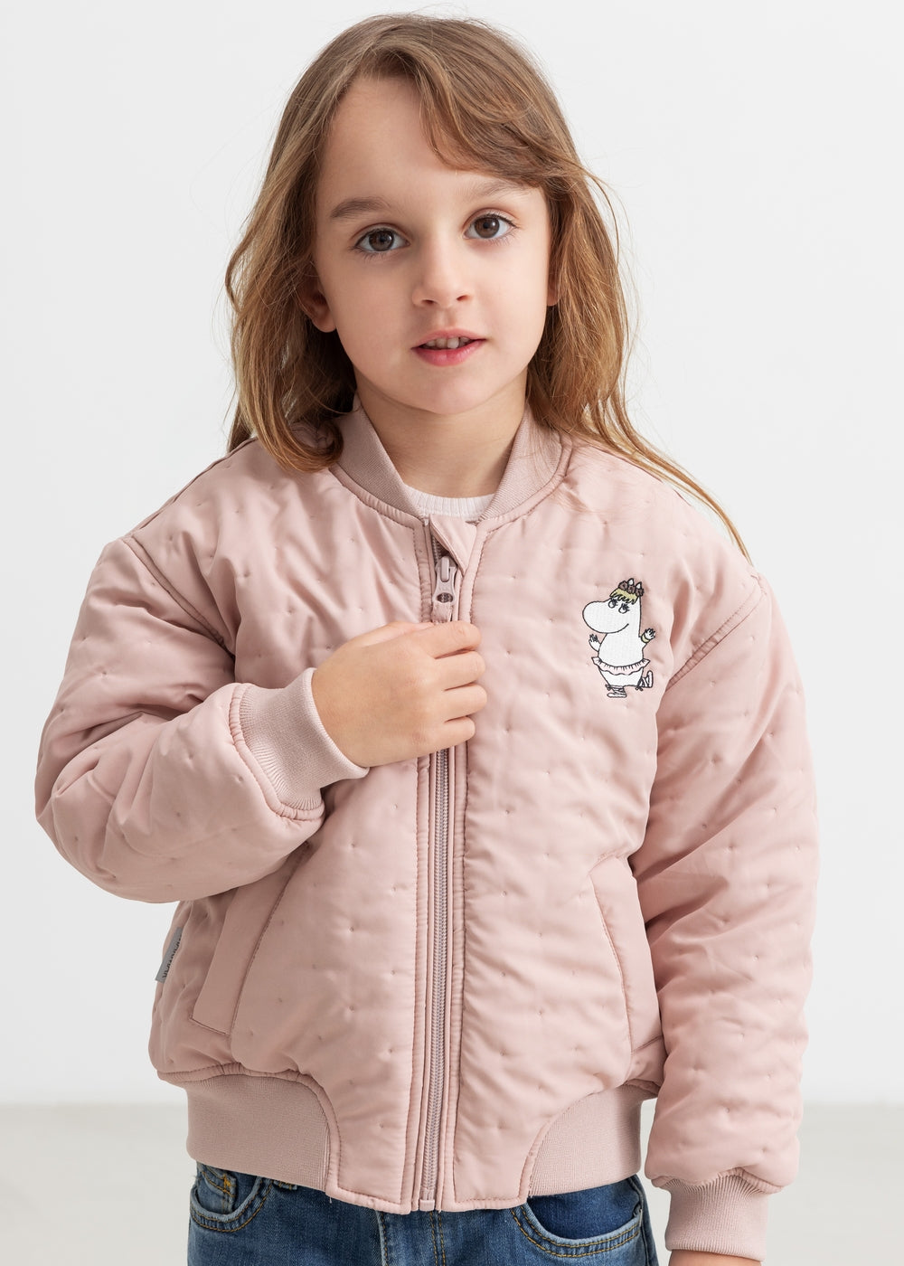 Child wearing a bright red quilted jacket with Moomin print.