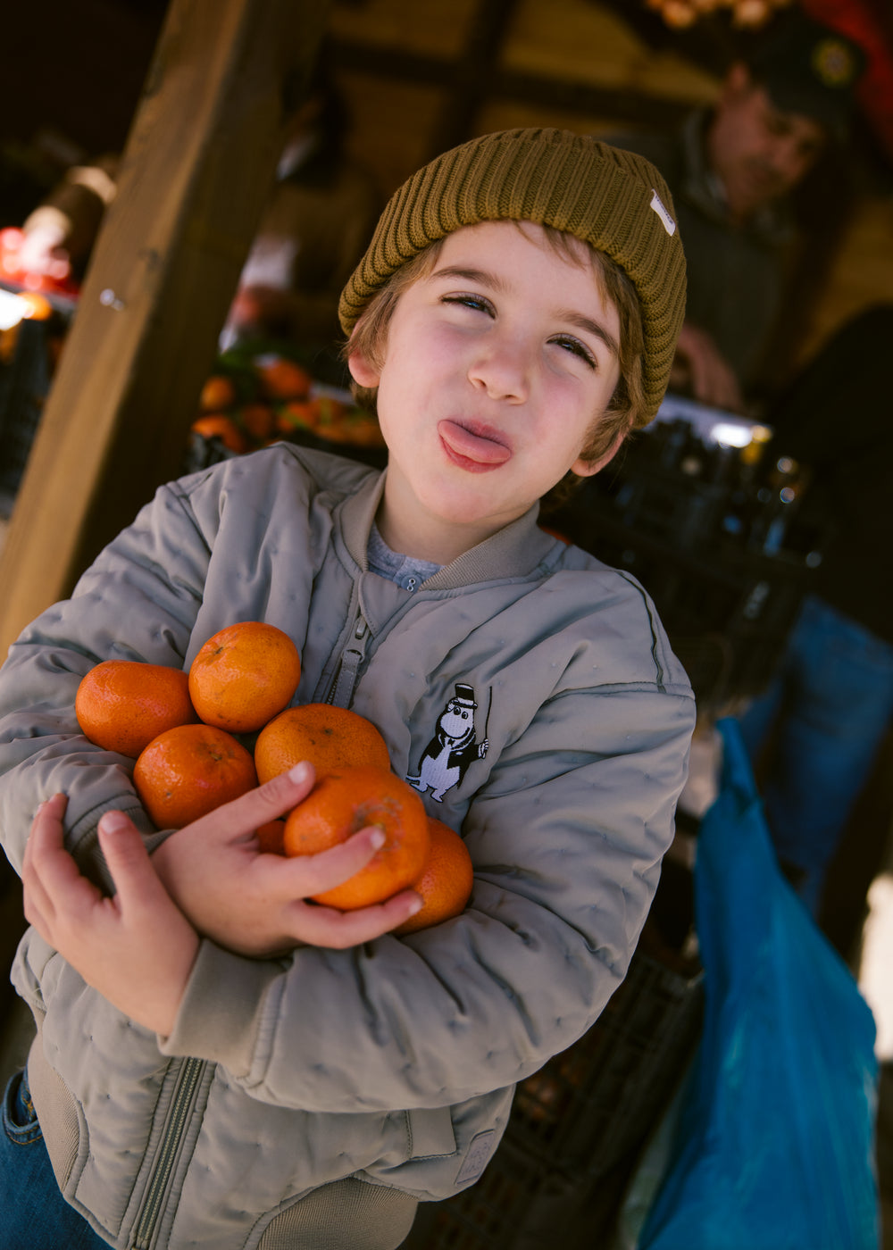 Children in green Moomin jackets holding fruit in their arms