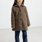 Pige iført brun ternet uldfrakke