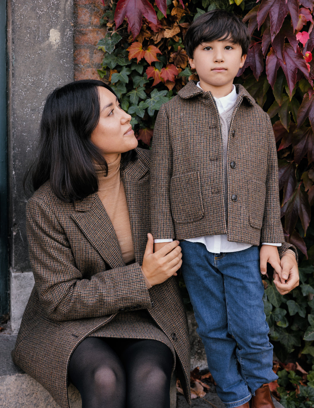 Kvinne og barn sammen, barnet iført brun ternet jakke.