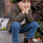 Barn i brun ternet jakke sidder på trappe