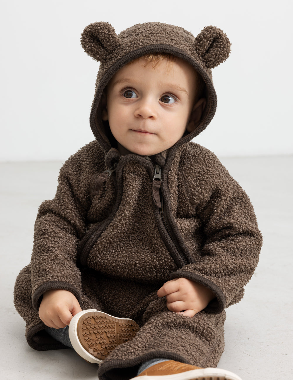 Baby i brun holdt med ører, sidder og kigger op