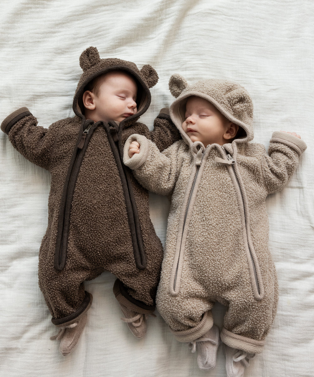 To babyer iført teddyheldragter, den ene i lys beige og den anden i brun