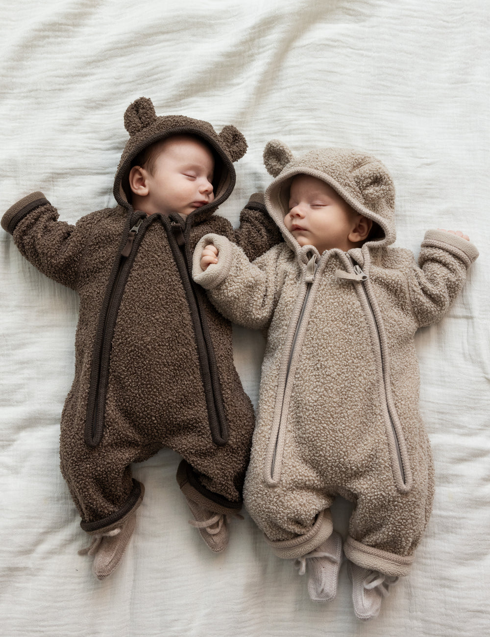 For babyer iført teddyheldragter, den ene i lys beige og den anden i brun