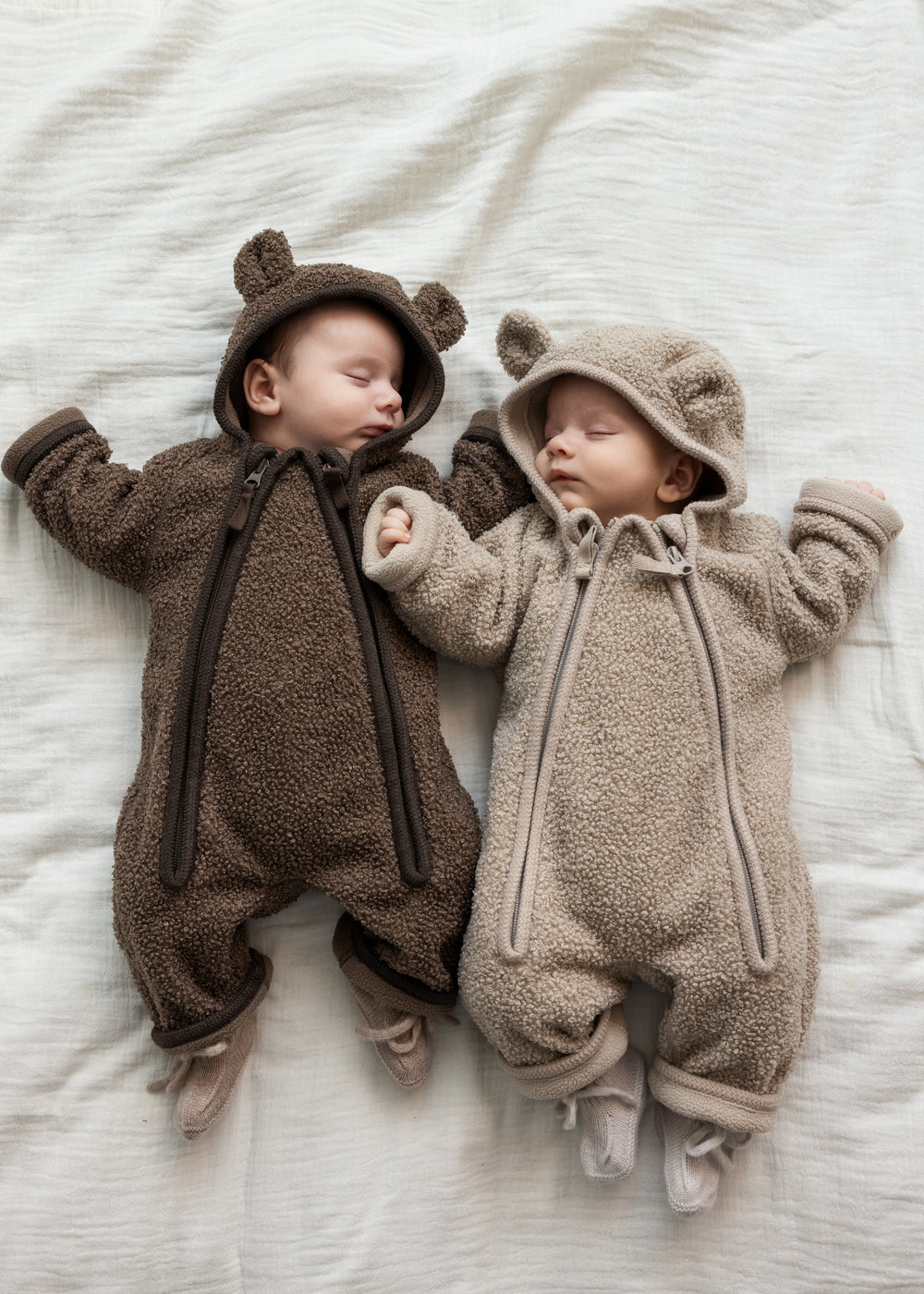 To babyer iført teddyheldragter, den ene i lys beige og den anden i brun