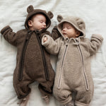 To babyer liggende iført teddyheldragter i lyse og mørke brune nuancer