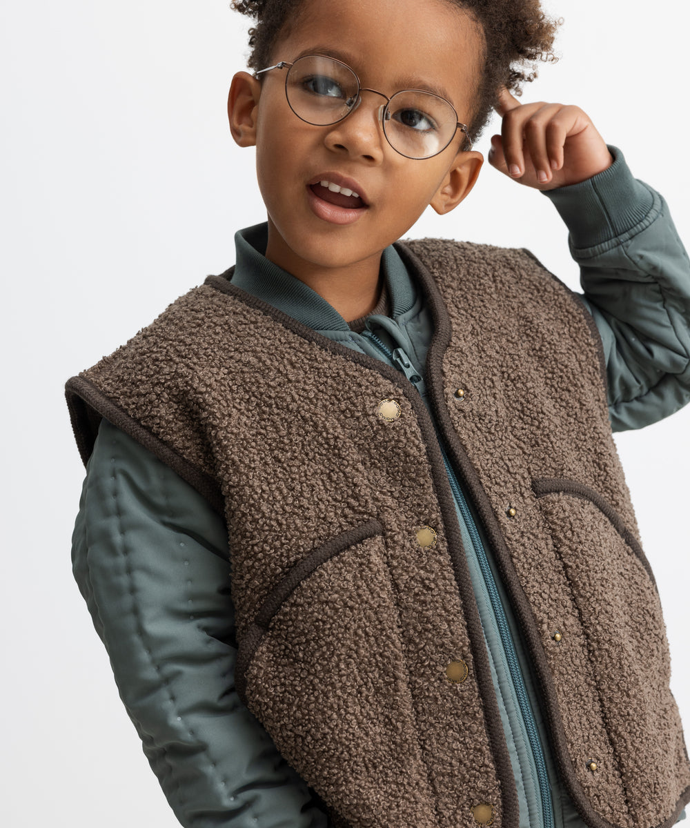 Barn iført brun teddyvest over jakke 