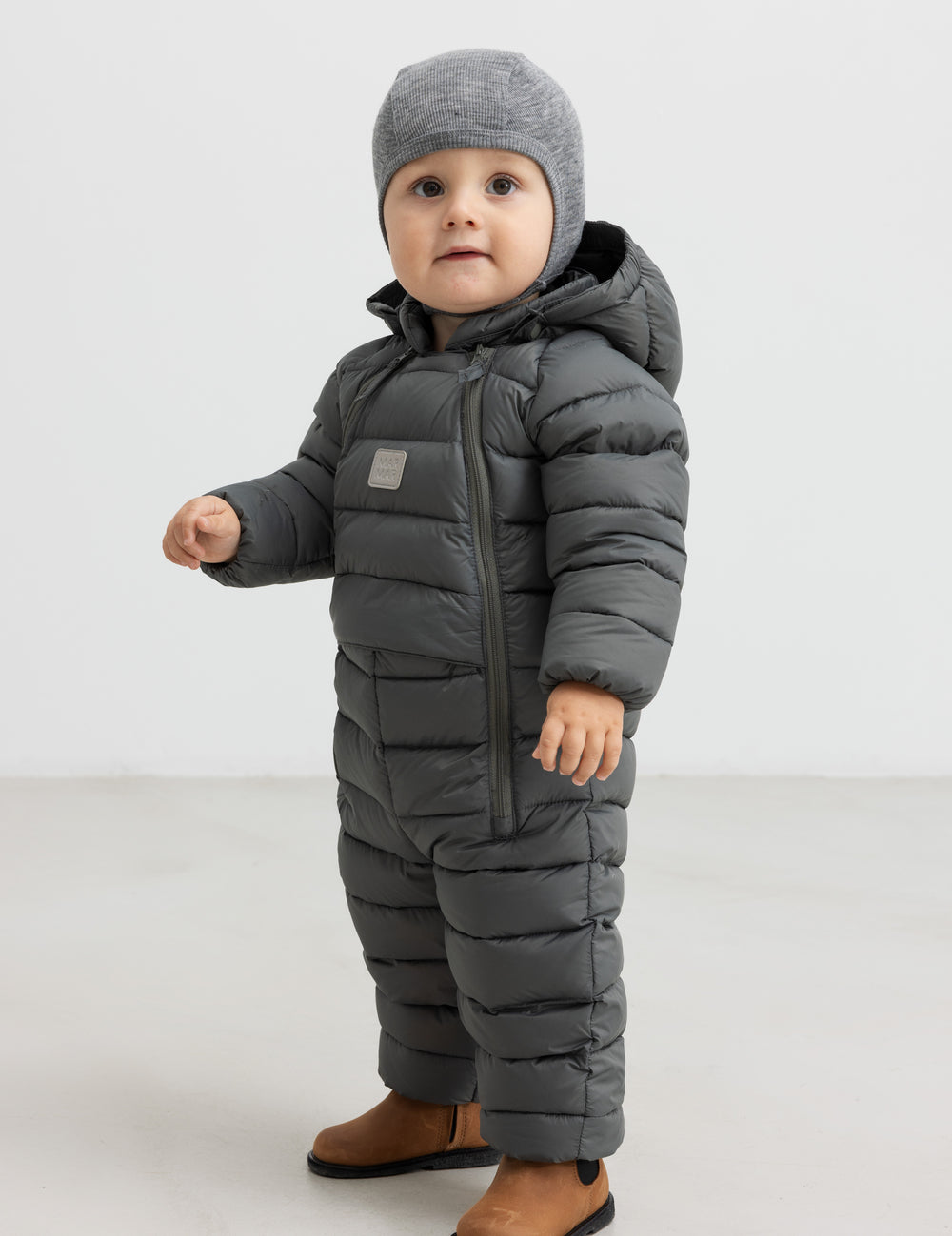 Baby iført mørkegrøn dundragt med hue