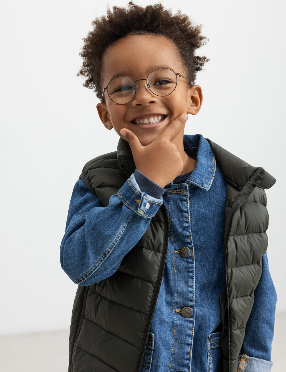 Dreng iført mørkegrøn vatteret vest over denimskjorte