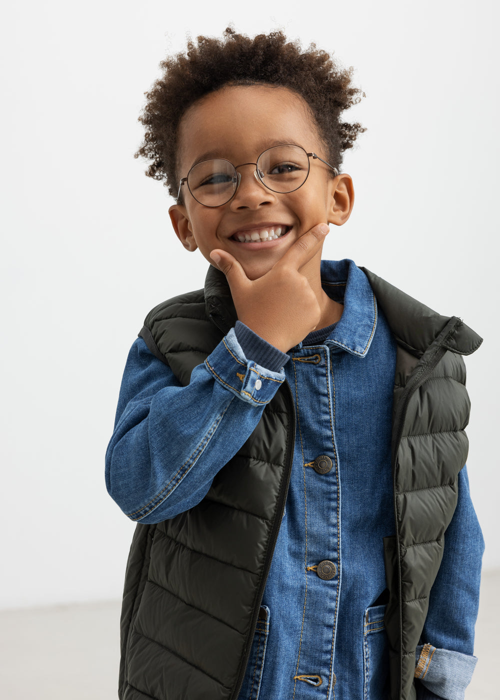 Dreng iført mørkegrøn vatteret vest over denimskjorte