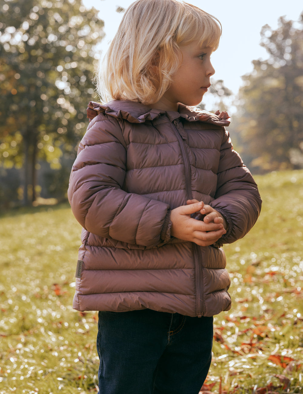 Børn leger i efterårsblade iført rosa vatteret jakke med flæsekrave.