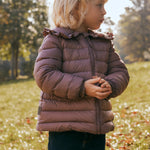 Børn leger i efterårsblade iført rosa vatteret jakke med flæsekrave