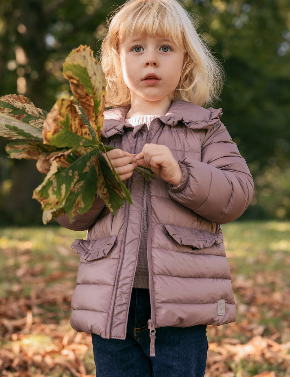 Pige i naturen iført rosa vatteret jakke med krave