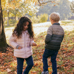 To børn iført vatterede jakker leger i efterårslandskab