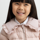 Barn i lyserød vatteret jakke med flæsekrave smiler