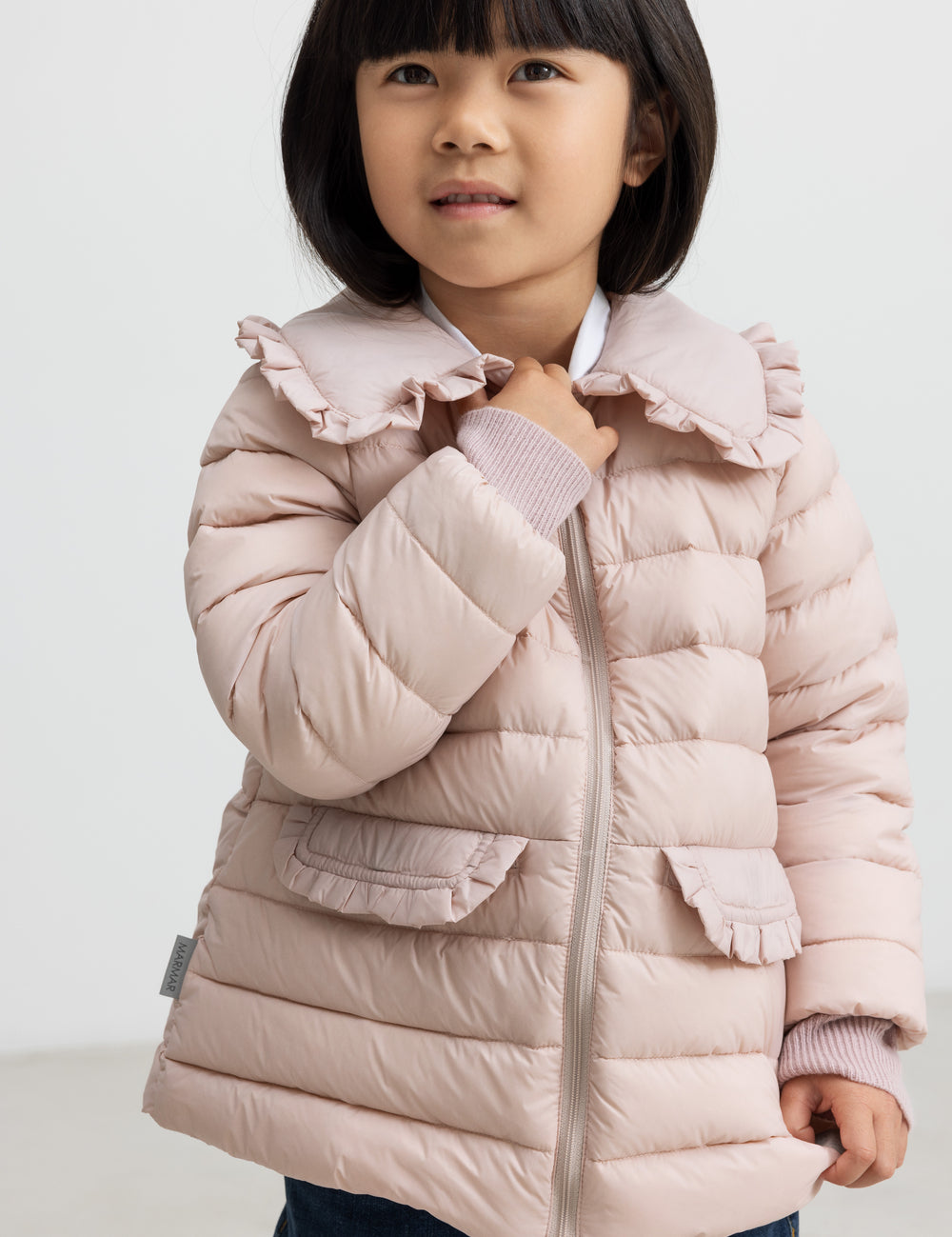 Pige iført lyserød vatteret jakke med flæsekrave