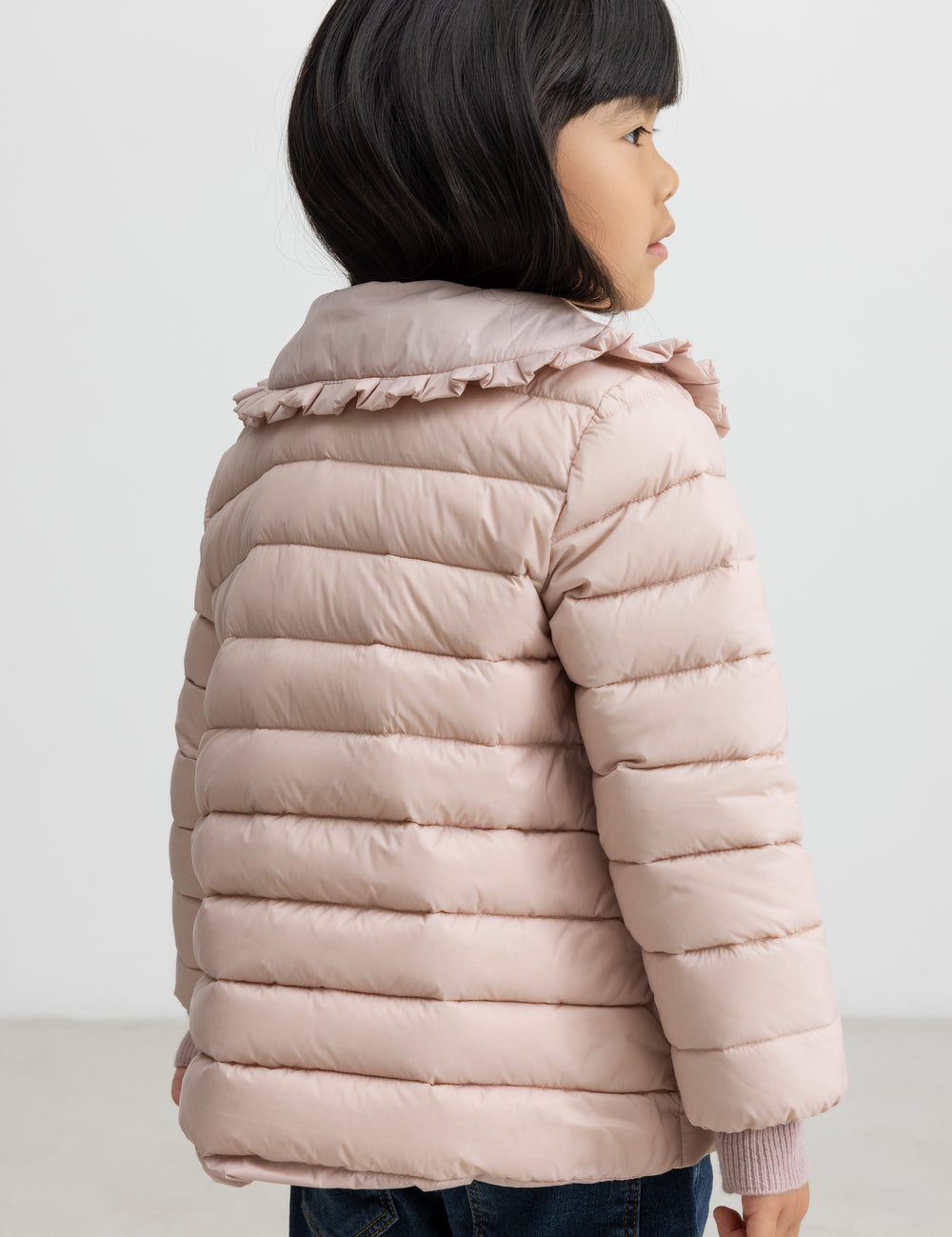 Pige med lyserød vatteret jakke set bagfra