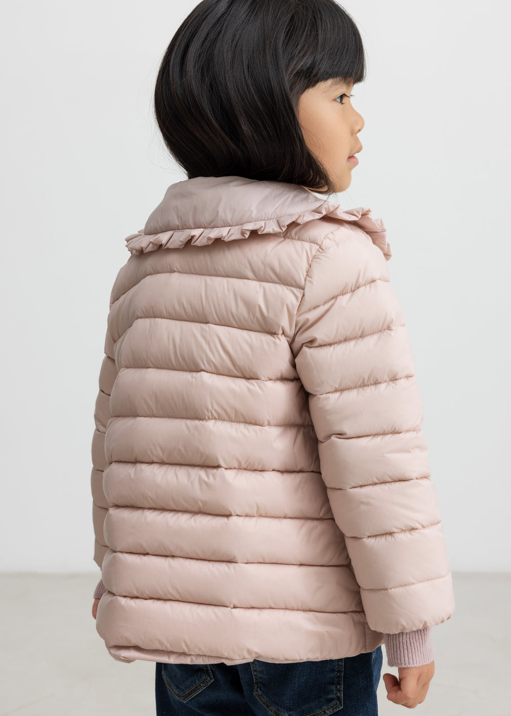 Pige med lyserød vatteret jakke set bagfra