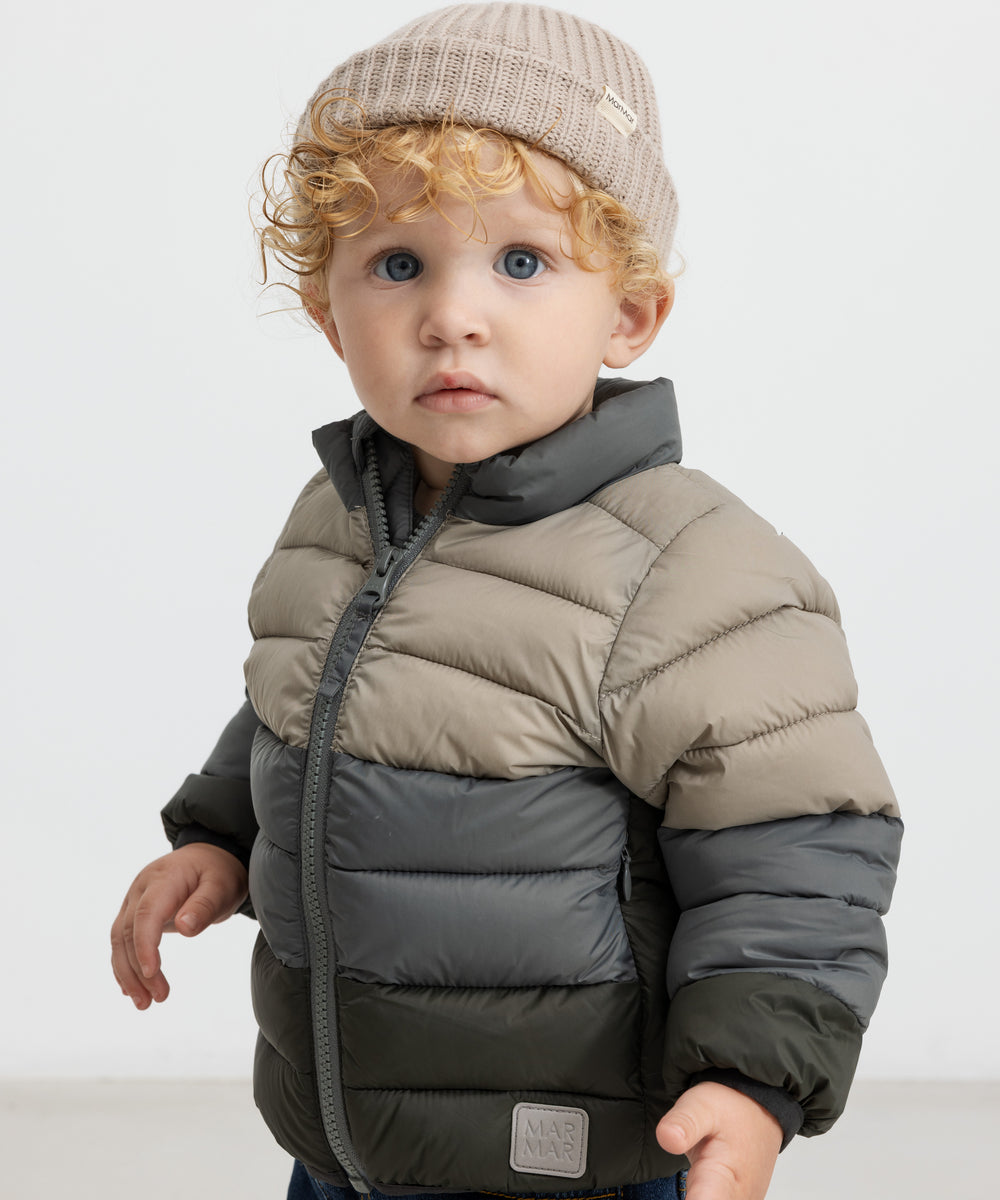 Barn iført beige strikhue og todelt dunjakke